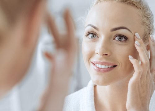 Woman with crow's feet looking at her face in the mirror