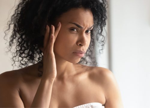 Woman looking at her glabellar lines in the mirror