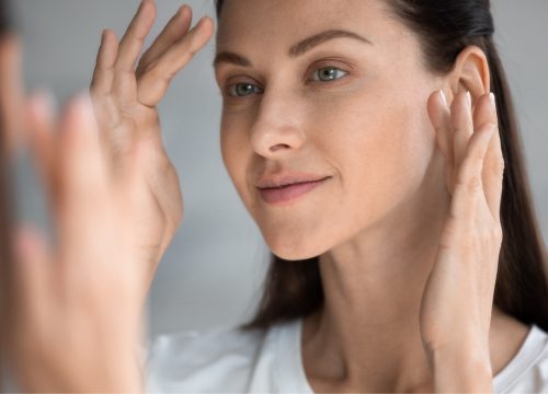 Woman with skin laxity looking at her face in the mirror