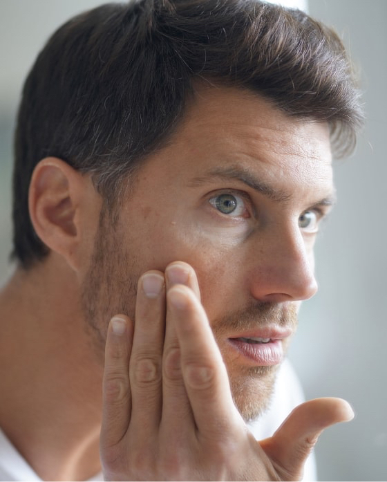 Man checking his skin in the mirror